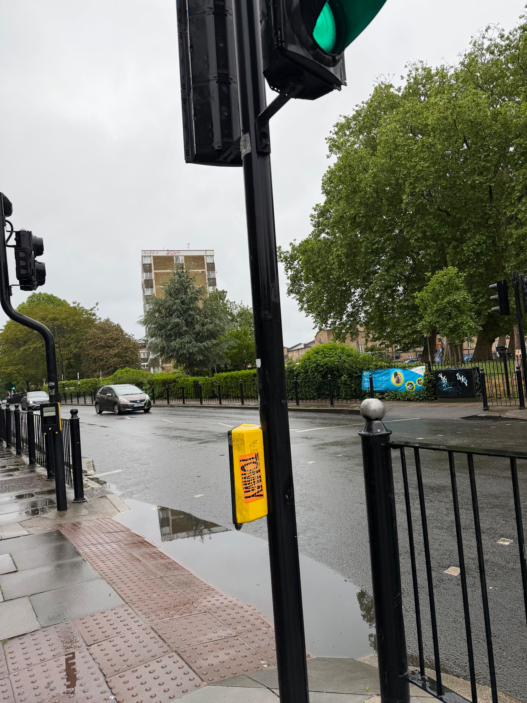 A muddy puddle on the lip of a pedestrian crossing with no drainage 