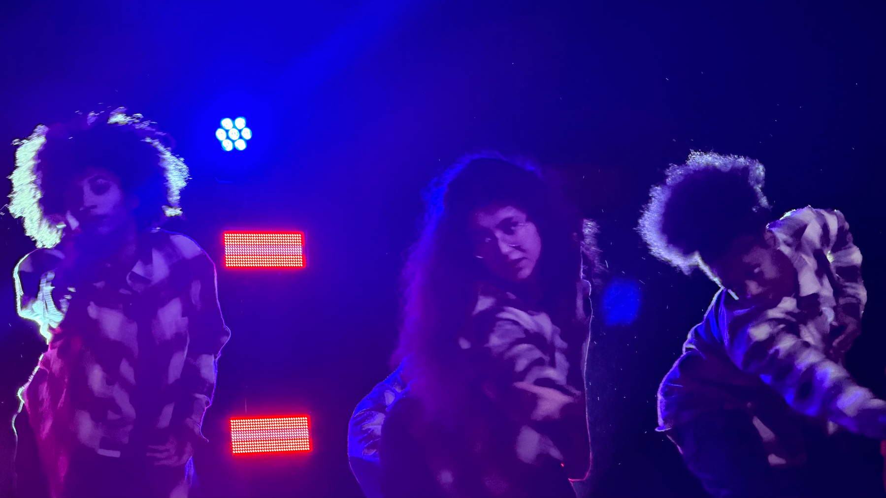 Three dancers, moodily lit from behind.